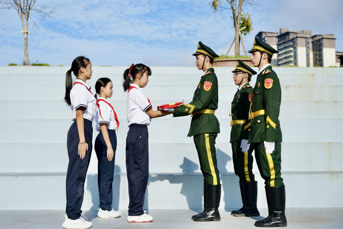 一面来自天安门广场的五星红旗在南宁二中凤岭校区护旗手和青运校区学生代表间共同传递。