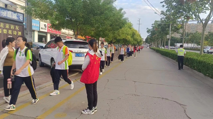 事发地点为校门口辅路，路边有广告牌、私家车和行道树。图片来源：佛山中学微信公众号
