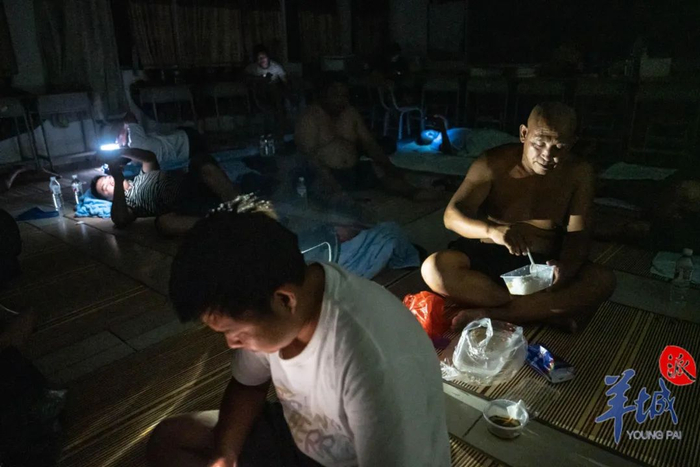 台风造成安置点断电，司机们借着手机微弱的光亮吃饭、休息