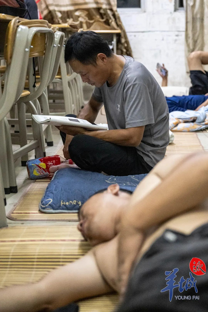 一位司机捧着安置点内一本高中课本认真地看，他的女儿也在读高中