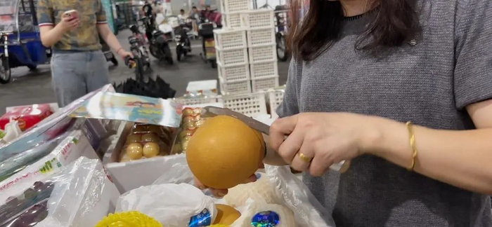 经营户切开秋月梨，邀请来往消费者品尝。