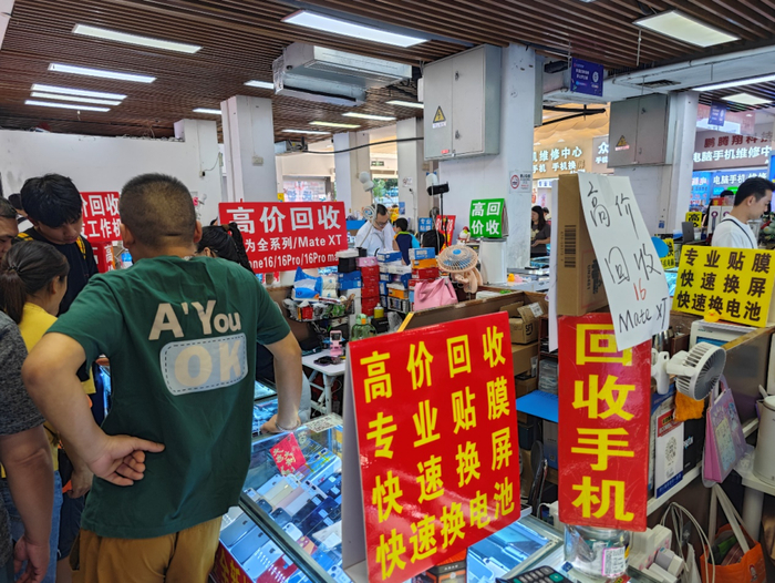 多家店铺均挂着“高价回收”Mate XT和iPhone 16的牌子。安宇飞/摄