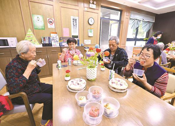             北新泾街道老年人日间照料中心内，老人们一起吃重阳糕 本报记者  王凯  摄          