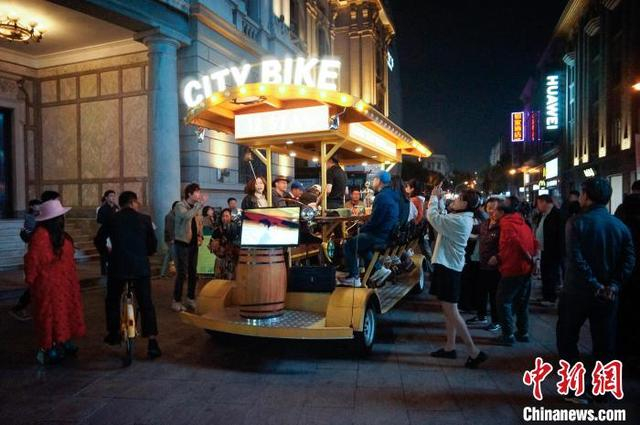 10月11日晚，天津，游客乘坐City Bike啤酒车夜游商业街。中新社记者 佟郁 摄