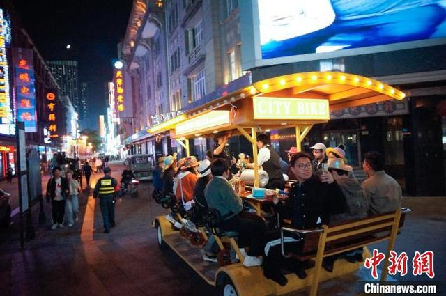 10月11日晚，天津，游客乘坐City Bike啤酒车夜游商业街。中新社记者 佟郁 摄