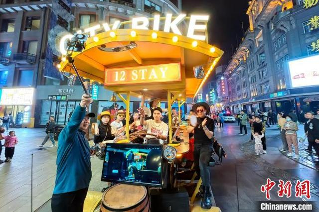 10月11日晚，天津，游客乘坐City Bike啤酒车夜游商业街。中新社记者 佟郁 摄