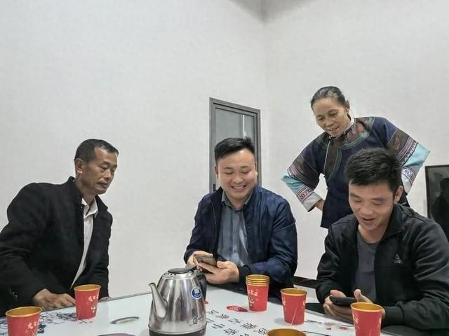 在村民田学军（左一）家中，农前朝（左二）和村民查看手机中的咖啡树照片。新华每日电讯记者 徐海涛 摄