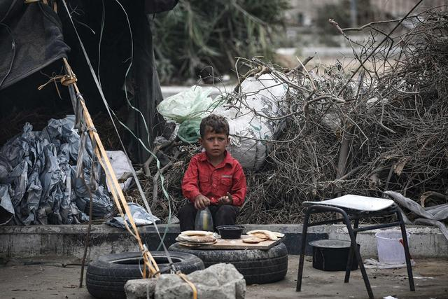 当地时间2024年10月17日，加沙地带代尔拜拉赫，一名巴勒斯坦儿童在临时避难所吃饭。视觉中国 图