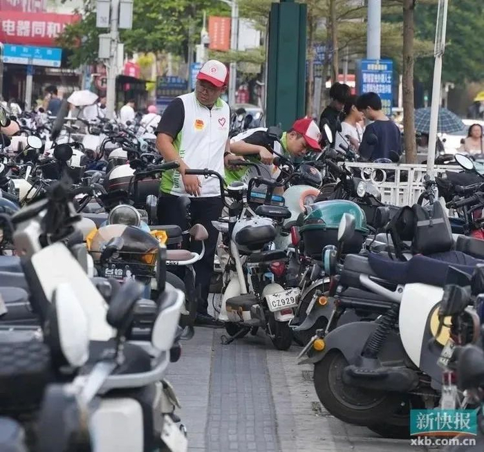 志愿者在地铁同和站附近整理乱停放的电动自行车。