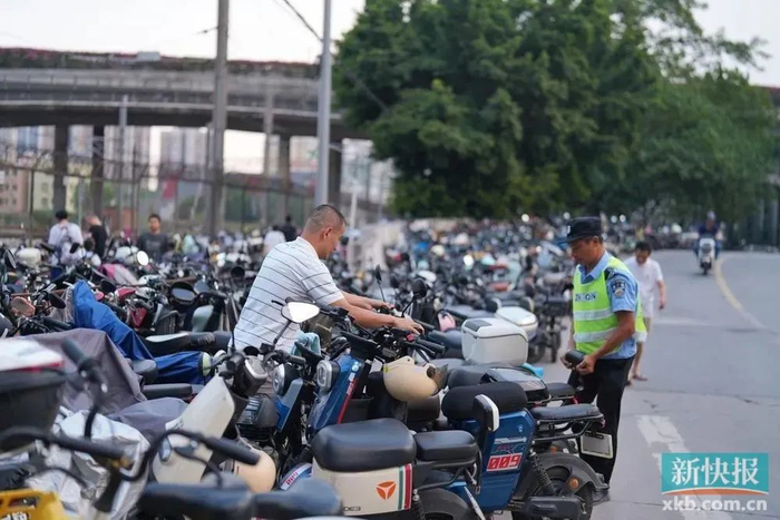 执勤人员在地铁坑口站附近整理乱停乱放的电动自行车。