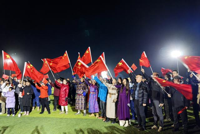 发射场观礼区，人们挥舞国旗为“神十九”加油。记者 高慧 摄