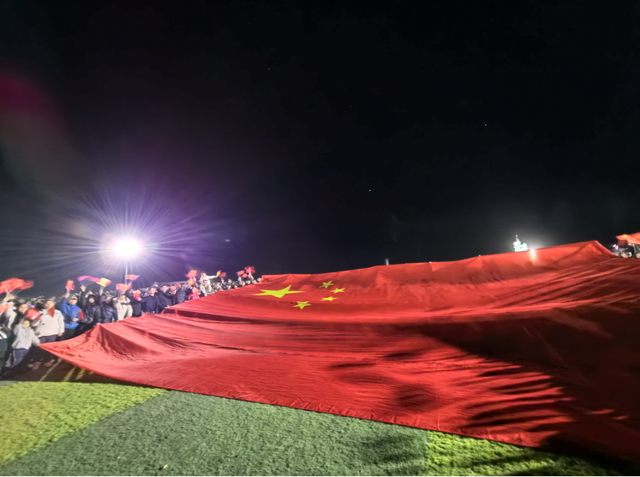 东风航天城发射场观礼点，额济纳群众托起巨幅国旗。记者 高慧 摄