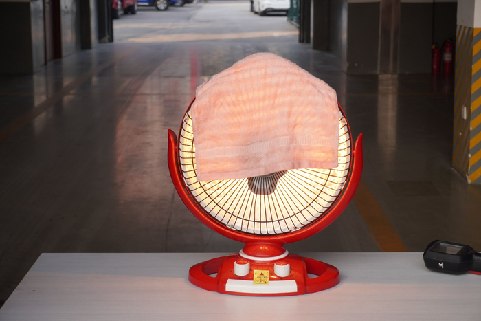 湿毛巾搭在高温状态下的“小太阳”上。 新京报记者 左琳 摄