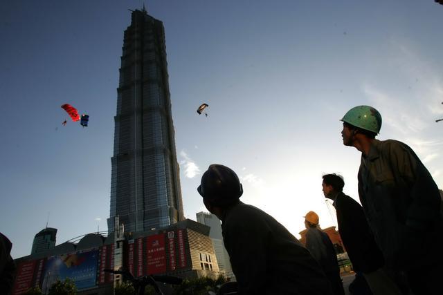 2003年10月6日，一群建筑工人在金茂大厦楼下观看低空跳伞表演。王杰 摄