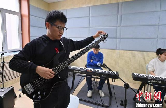 11月14日，吉林长春，“逐暗逐光”乐队发起者楼林昊天在调贝斯。中新社记者 张瑶 摄 
