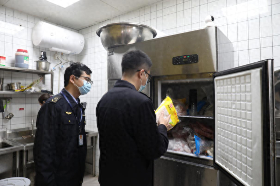 图为工作人员在餐厅后厨检查食品安全