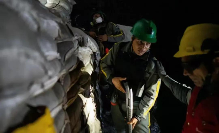 紫金矿业保安负责人在阻止非法矿工进入的障碍物前与公司武装警卫交谈/图源：华尔街日报