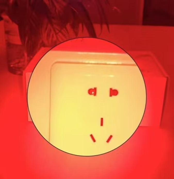 ▲昏暗环境下，防偷拍检测仪器检测到针孔摄像头时，会反射出红色光点（左侧插孔）。受访者供图