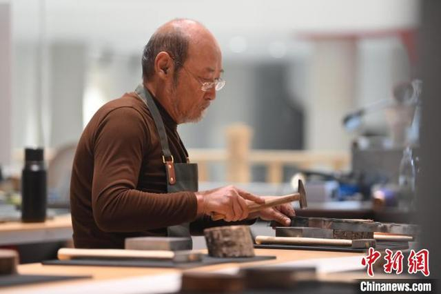 11月23日，甘肃省兰州市杨树珍剪纸工作室内，工匠名师刘金碌制作剪纸汉服作品的金属帽边。中新社记者 李亚龙 摄