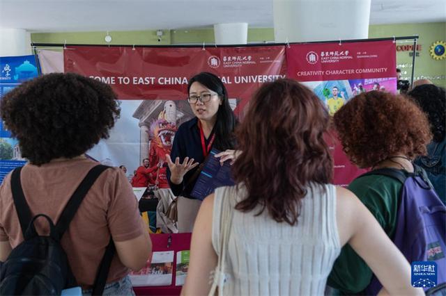 11月25日，在巴西里约热内卢联邦大学举行的中国高等教育展上，参观者与一名宣介人员（中）交流。新华社记者 王天聪 摄