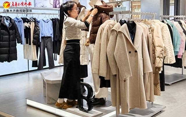 　　在乌鲁木齐友好南路附近一家商场，服装店工作人员正在给模特换上新款羽绒服。 记者王璇摄