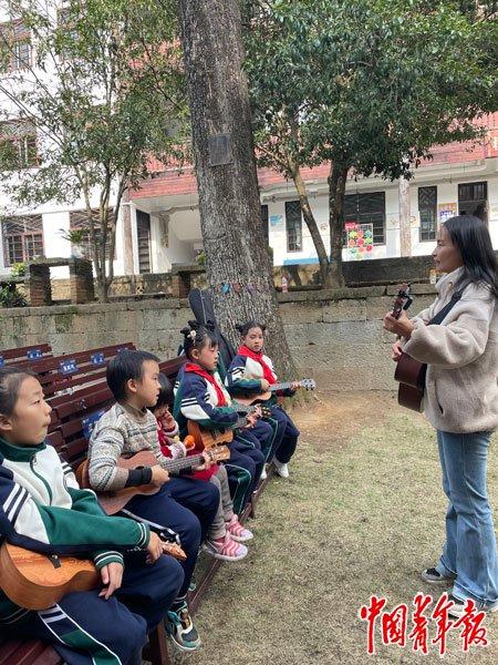     11月23日，浙江诸暨斯民小学，一位家长在教一群孩子弹吉他。