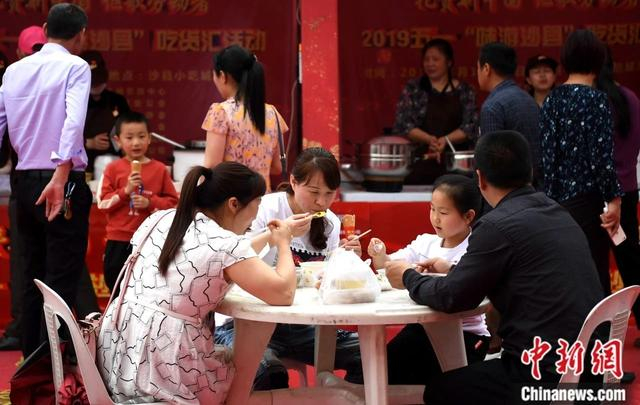 图为家长带着小孩在现场品尝刚购买的沙县小吃。中新社记者 张斌 摄