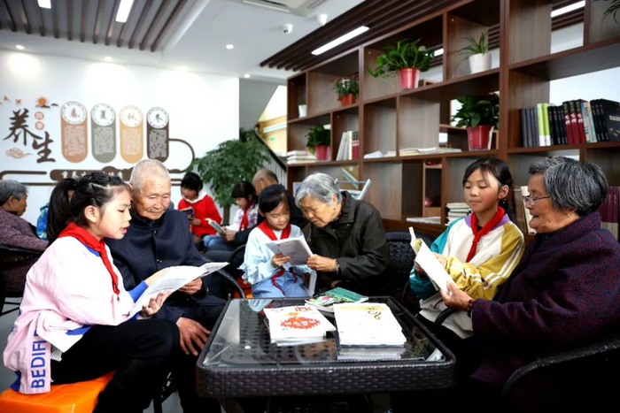 △在浙江省长兴县太湖街道新开河村居家养老中心，孩子们在为老人读书。新华社发