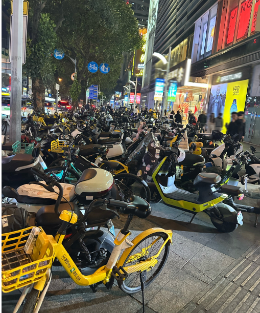 人行道上停着大量电动自行车、共享单车；摄/张晓慧