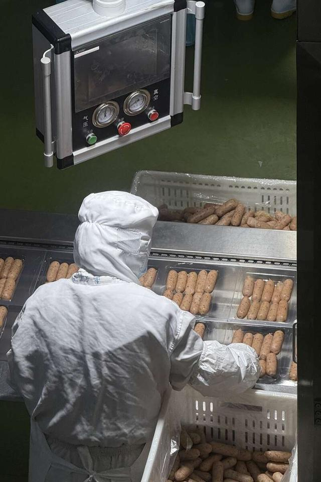 河南华昱控股有限公司的生产车间里，工作人员正在调整成品烤肠在包装盒中的位置。中青报·中青网见习记者 李梓昂/摄