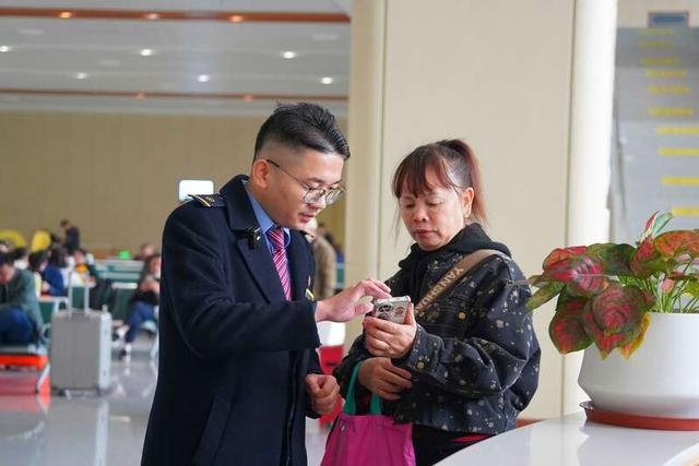 东兴市站客运值班员罗团雄为旅客解答疑问。农姿旋/摄