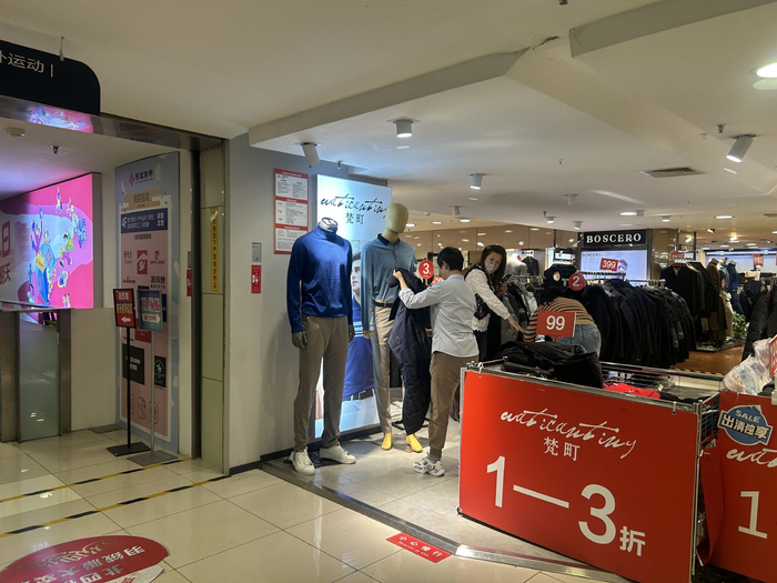 售货员整理模特身上的衣服，一边招呼顾客一边打包。新京报记者 王贵彬 摄 