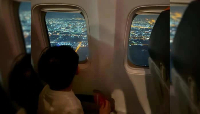 男孩在飞往泰国曼谷的飞机上向窗外张望。