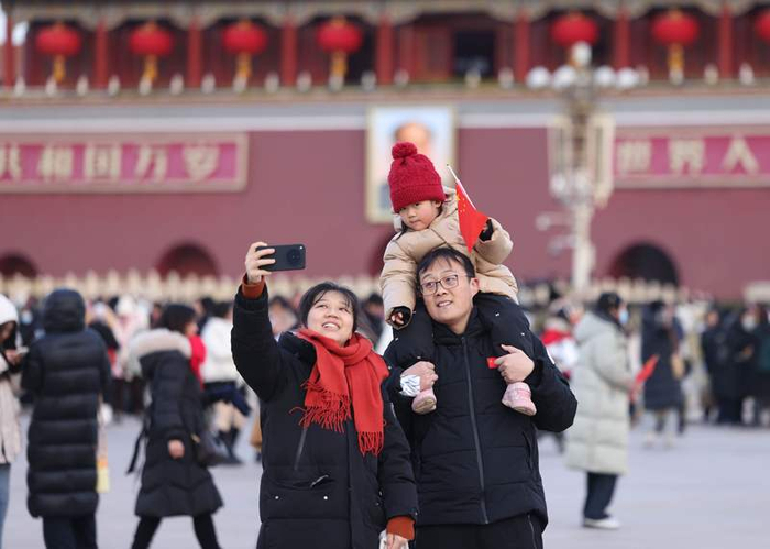 小朋友手持国旗和爸爸妈妈自拍。新京报记者 李木易 摄