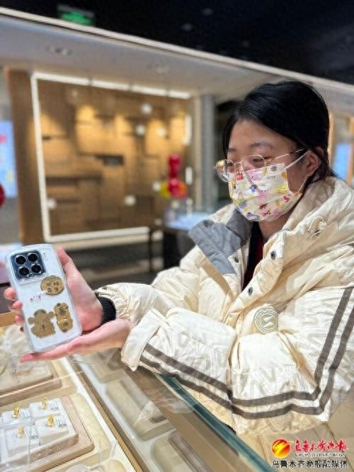 　　1月8日，在美美负一楼金店，市民邱维向记者展示她贴在手机背后的黄金贴纸。记者向雅祺摄