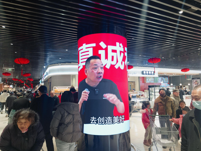 超市入口处播放着“于东来”的演讲视频