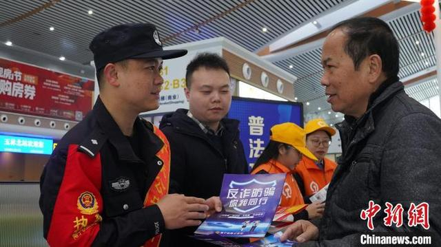 民警在玉林北站候车室普法宣传点向旅客开展“反诈”宣传。姚鹏鹏 摄