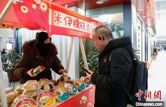 1月14日，旅客在西宁火车站非遗集市上购买青海特色美食八宝饭、酥合丸。中新社记者 马铭言 摄 