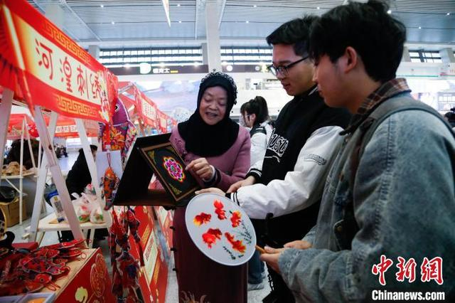 1月14日，西宁火车站，旅客在非遗集市上了解青绣。中新社记者 马铭言 摄 