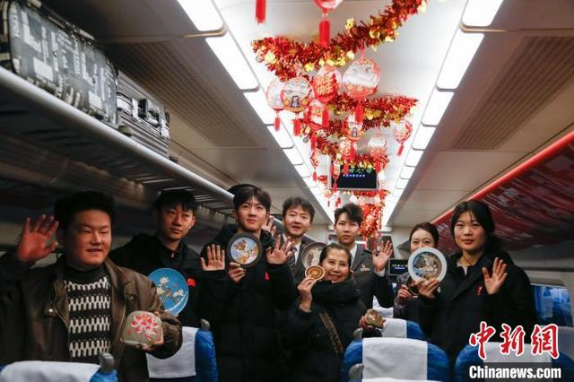 1月14日，西宁火车站，旅客在车厢内了解景泰蓝掐丝唐卡，并于乘务人员合影留念。中新社记者 马铭言 摄 