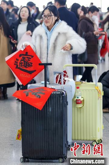 图为旅客带着书法家书写的“招财进宝”和“福”字候车。中新社记者 泱波 摄 