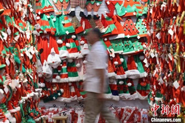 近日，一名采购商从浙江义乌市场的圣诞帽档口走过。董易鑫 摄