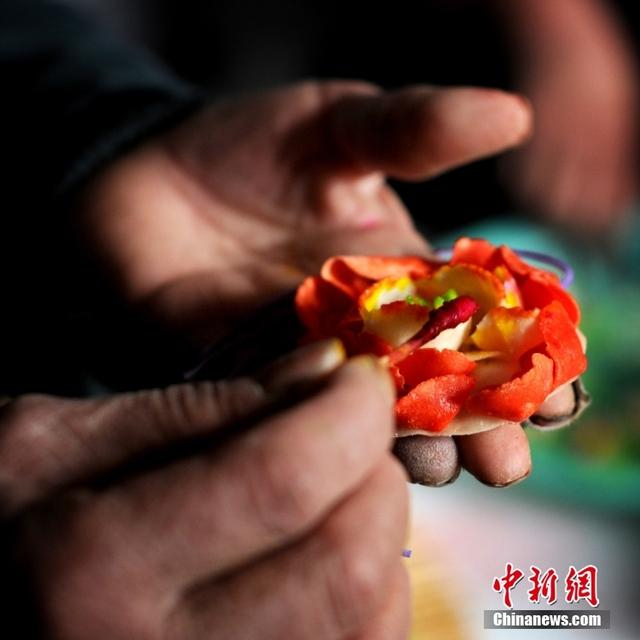 图为闻喜花馍艺人在捏制一朵面花。