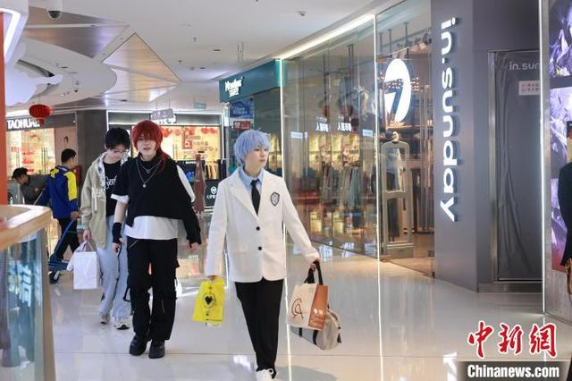 图为身穿漫画形象服装的年轻人在逛“谷子店”。中新社记者 林馨 摄