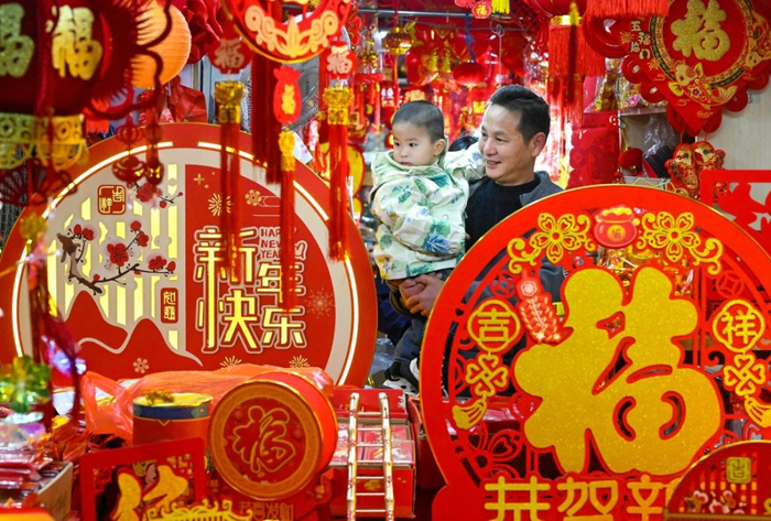 1月24日，一对父子在浙江省宁波市镇海年货市场采购春节饰品。新华社 图
