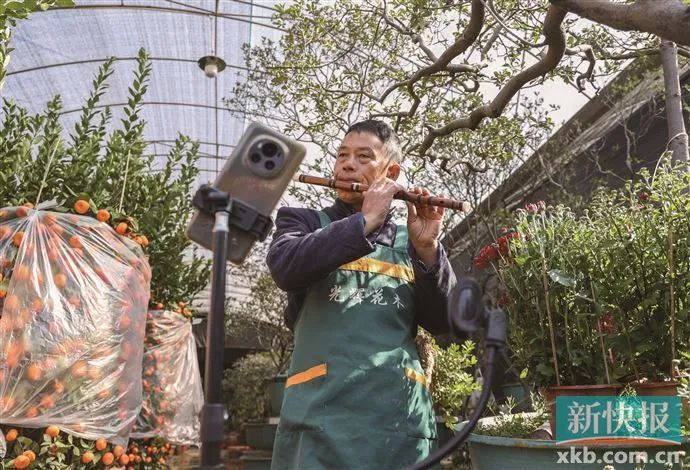 西约花卉市场，一摊主在直播平台展示才艺，吸引线上客户。