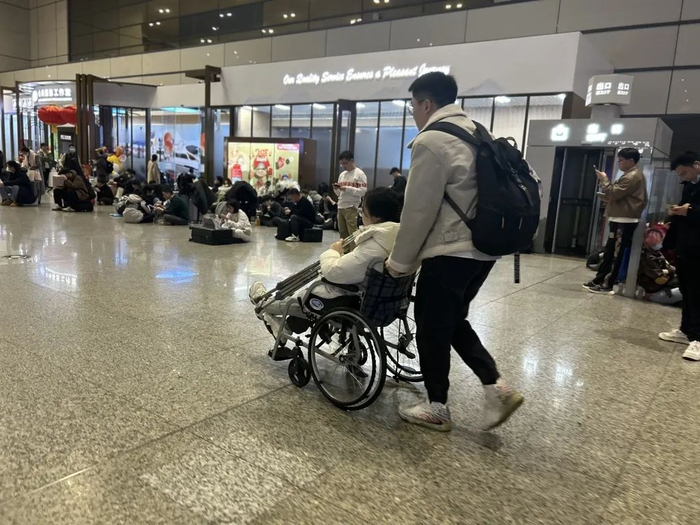1月25日凌晨，上海虹桥火车站，包先生用轮椅推着女友。