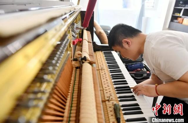 黄延平在张女士家进行钢琴调律。中新社记者 吕明 摄