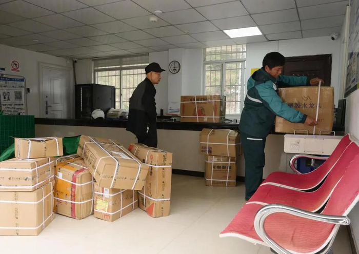 桑南才在称杆乡邮政所内协助当地老乡捆扎邮寄品 李贺 摄
