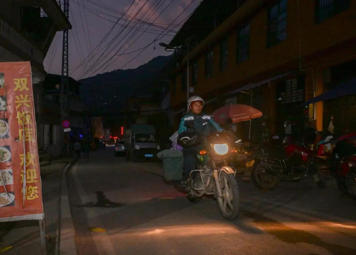 早晨7时许，桑南才骑着摩托车载着满满的邮包出发 李贺 摄